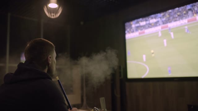 Man Watching Football And Smoking Hookah