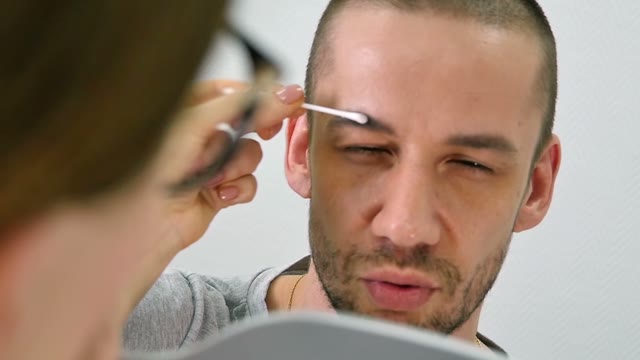 Girl Prepares To Paint A Man's Eyebrows Close-up