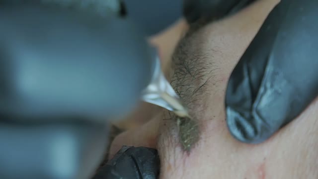 Master Does Tattoo Of Man's Brows Close-up
