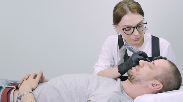 Woman Does Tattoo Of Man's Brows Close-up