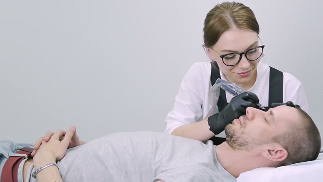 Woman Does Tattoo Of Man's Brows Close-up