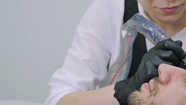 Woman Does Tattoo Of Man's Brows Close-up