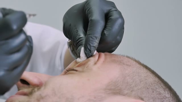 Master Does Tattoo Of Man's Brows Close-up