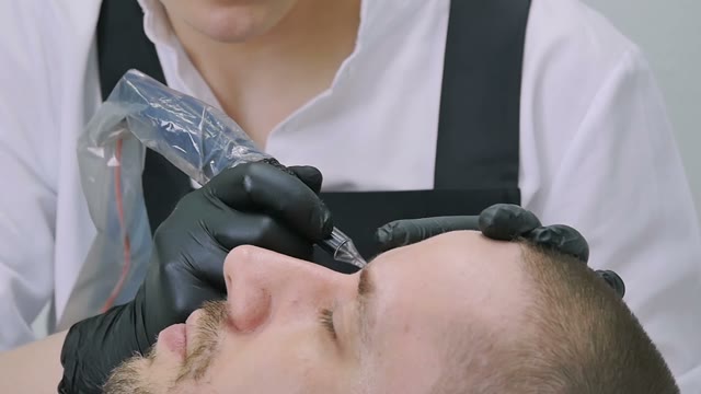 Master Does Tattoo Of Man's Brows Close-up