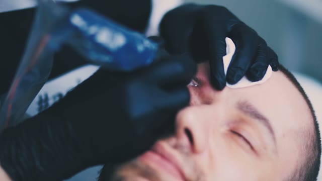 Woman Does Tattoo Of Man's Eyebrows Close-up