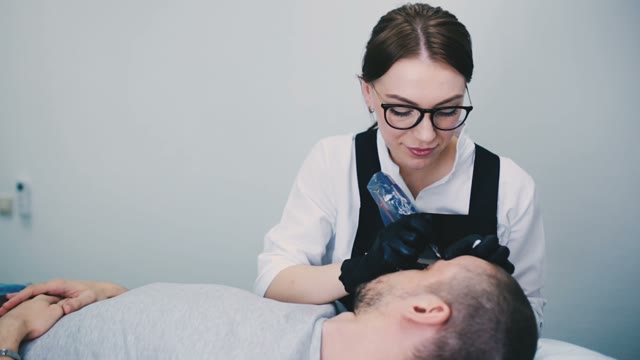 Woman Does Tattoo Of Man's Eyebrows Close-up