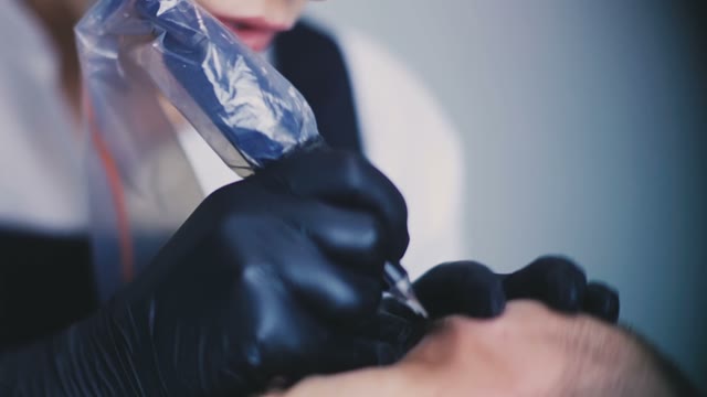 Woman Does Tattoo Of Man's Eyebrows Close-up