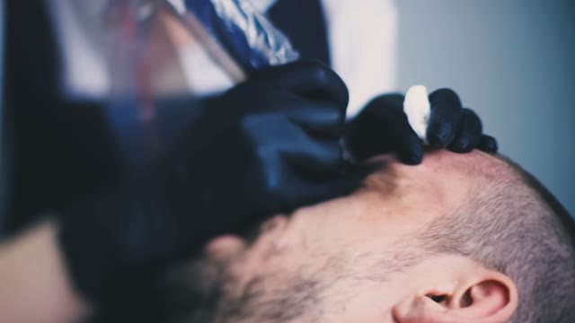 Master Does Tattoo Of Man's Brows Close-up