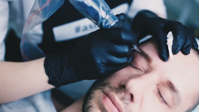 Master Does Tattoo Of Man's Brows Close-up