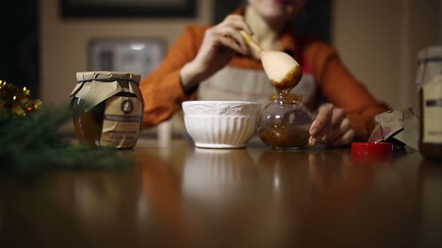 Woman Puts Honey In A Jar Close Up