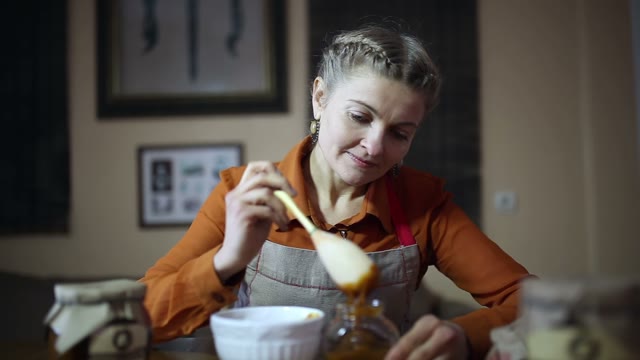 Woman Puts Honey With A Wooden Spoon