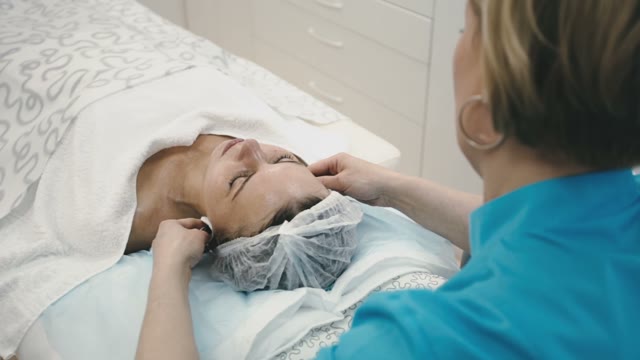 Woman From The Spa Salon Treats The Face Of The Girl With Different Creams
