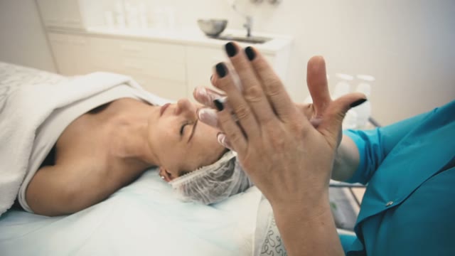 Employee Of The Spa Salon Prepares To Apply Cream On The Face Of The Girl