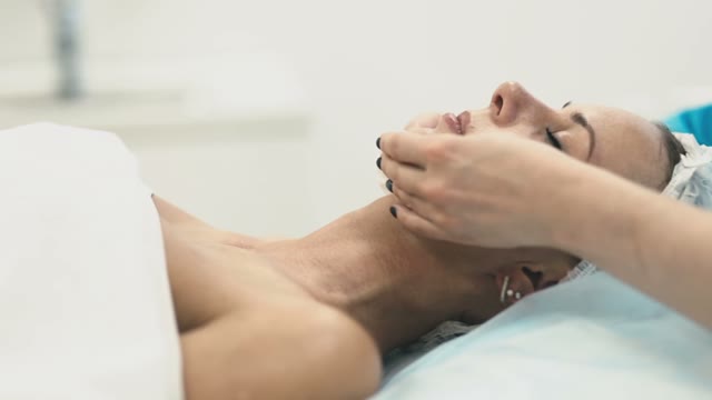 Employee Of The Spa Salon Treats The Face Of A Young Beautiful Girl With Cotton