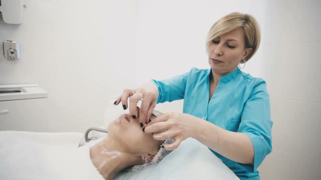 Woman From The Spa Makes A Facial Massage For A Young Beautiful Girl