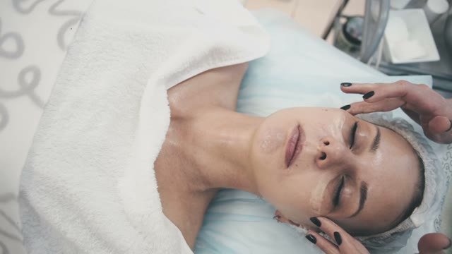 Employee Of The Spa Salon Rubs Cream Into The Skin Of A Young Attractive Girl