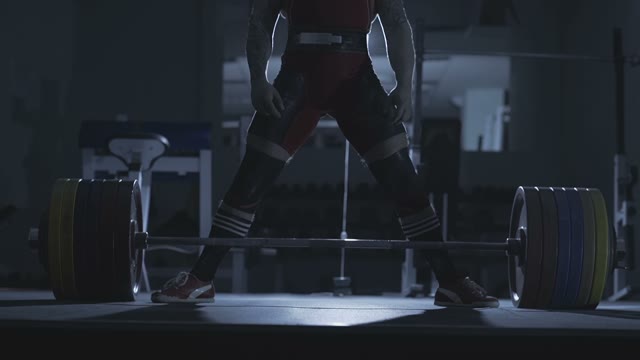 Man Is Standing Over A Barbell