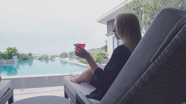 Girl With A Glass Sits By The Pool