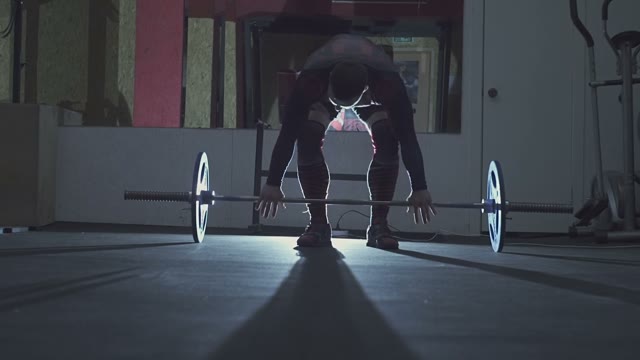 Man Lifts A Barbell In The Light Of The Searchlight