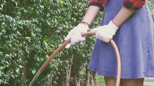 Girl Watering Plants From A Hose