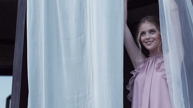 Girl Is Standing By The Curtains And Smiling
