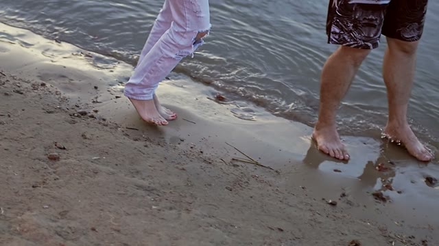 Young Couple Walking Along The Sandy Coast