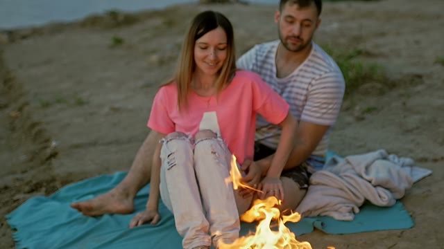 Young Couple On The Shore Look At The Bonfire