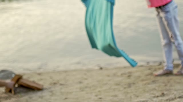 Girl Is Laying A Blanket On The Sand