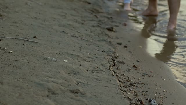 Guy And The Girl Are Walking On The Wet Sand