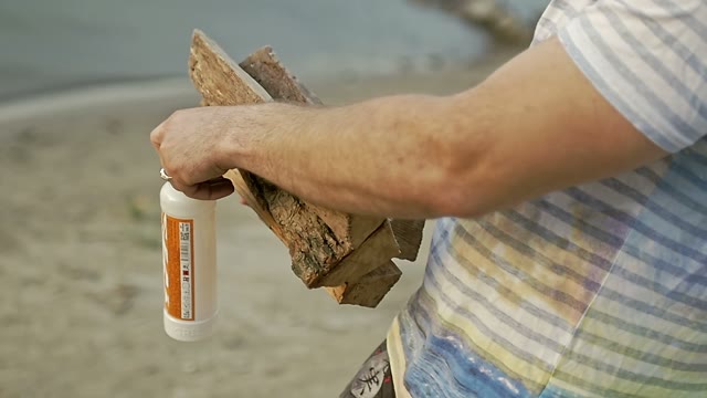 Guy Carries The Wood And The Ignition And Puts Them On The Sand