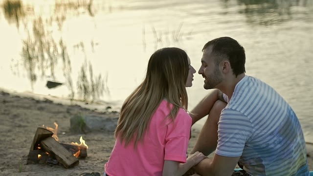 Young Couple Sitting On The Beach And Kissing