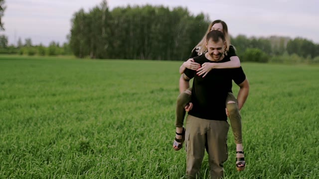 Girl Is Sitting At The Guy On The Back In The Field