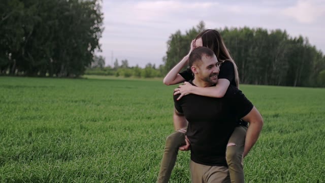 Guy Is Walking Along The Field With The Girl On The Back
