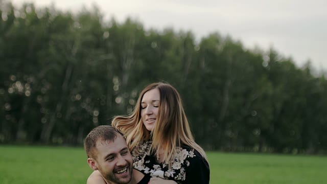 Girl Sits On The Back Of A Guy And Kisses Him On The Cheek