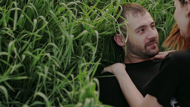 Young Couple Lies On The Grass And Looks At Each Other