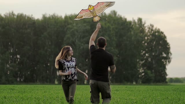 Young Couple Is Running Behind A Kite