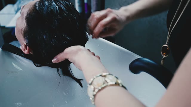 Hairdresser Washes The Client's Hair With Shampoo