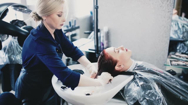 Girl Gently Flushes The Paint From The Client's Hair
